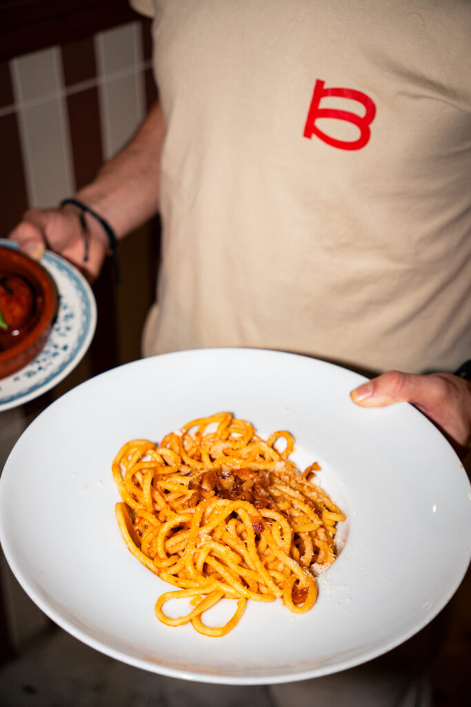 Un serveur qui tient une assiette de spaghetti carbonara en main