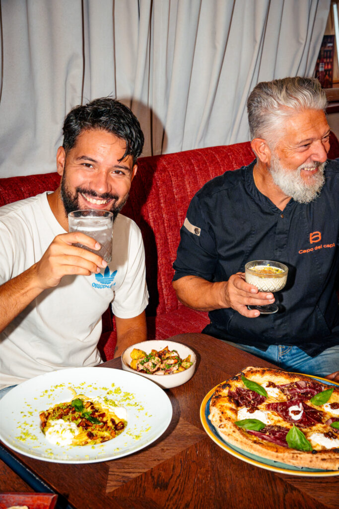 Simon et Marco trinquent à table devant des plats italiens