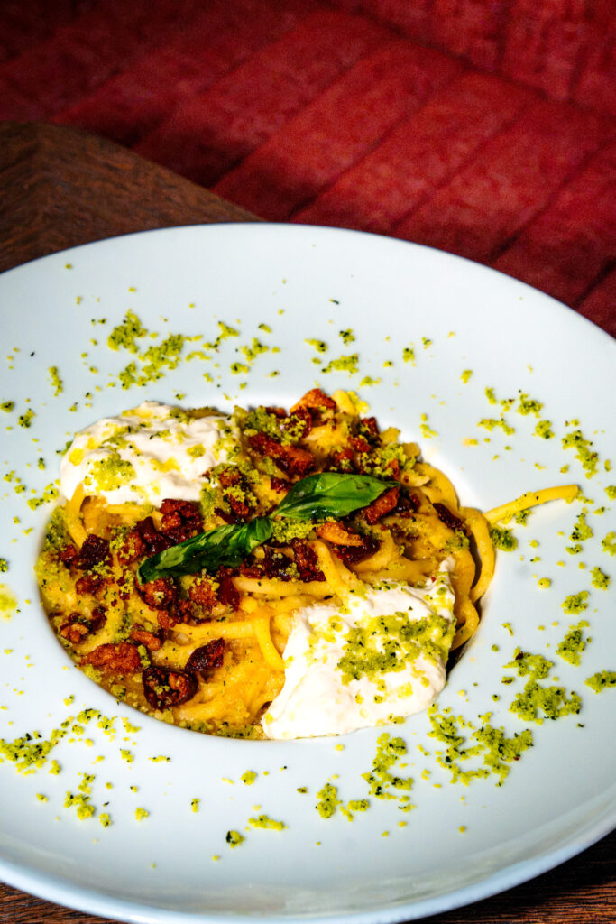 Une assiette de pâtes fraîches avec du lard émietté et de la stracciatella par dessus