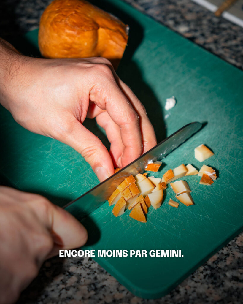une main qui découpe un morceau de fromage italien sur une planche à couper verte avec le texte "encore mois par gemini"