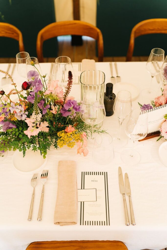 Une table dressée vue de haut avec des fleurs comme centre de table, le menu et une nominette placée par dessus